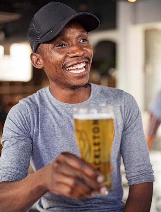 man smiling with a Shackleton beer in hand